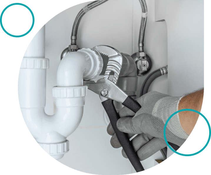 Plumber fixing under-sink pipe with wrench.
